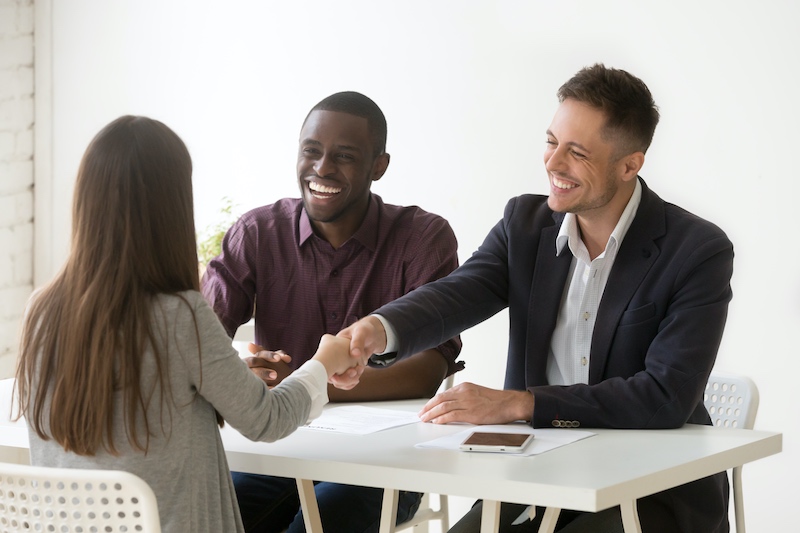 Friendly executives and successful candidate shaking hands across a desk